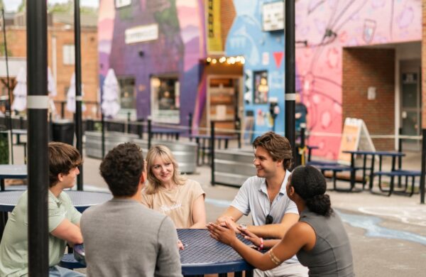 Friends sitting on a patio with street art in the background in Blacksburg Virginia