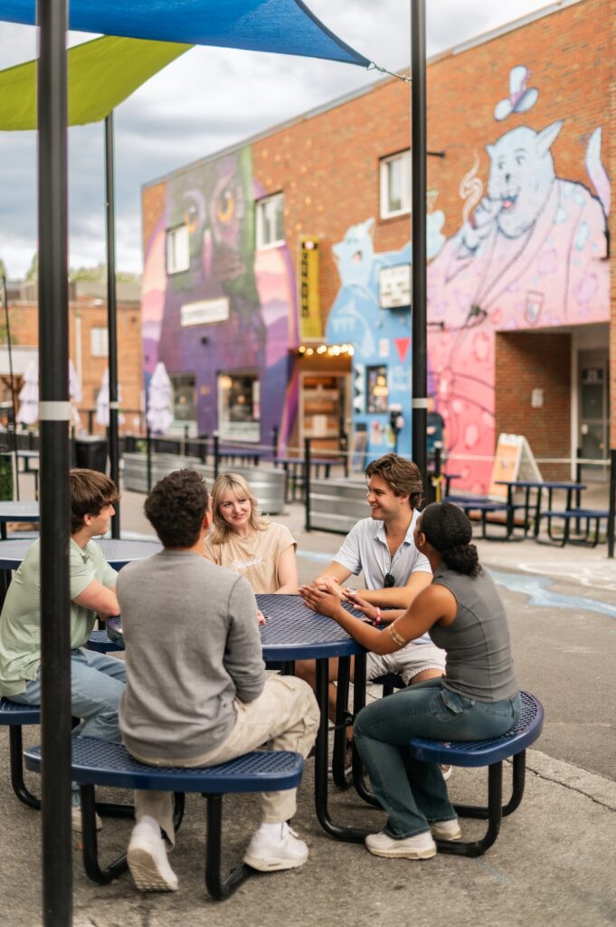 Friends sitting on a patio with street art in the background in Blacksburg Virginia