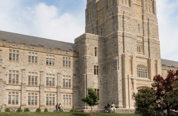 Group of friends taking a photo on the grass in front of a historic campus building at Virginia Tech