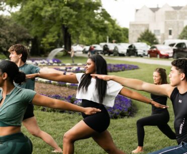 Group of young men and women practicing yoga outside on the Virginia Tech campus