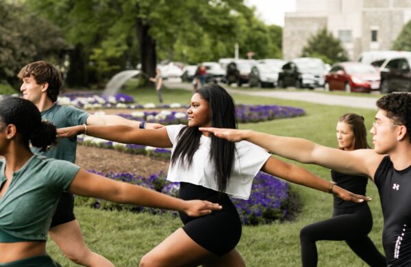 Group of young men and women practicing yoga outside on the Virginia Tech campus