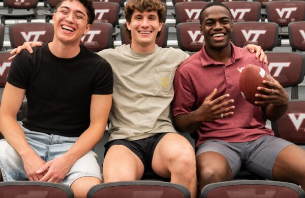 Three boys sitting in the stands of the Virginia Tech football stadium