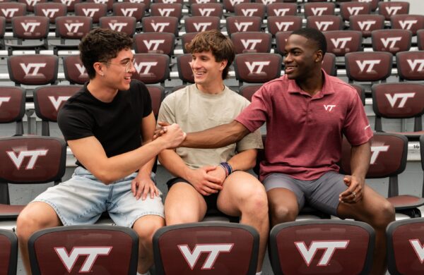 Three young men sitting in the stands of Lane Stadium