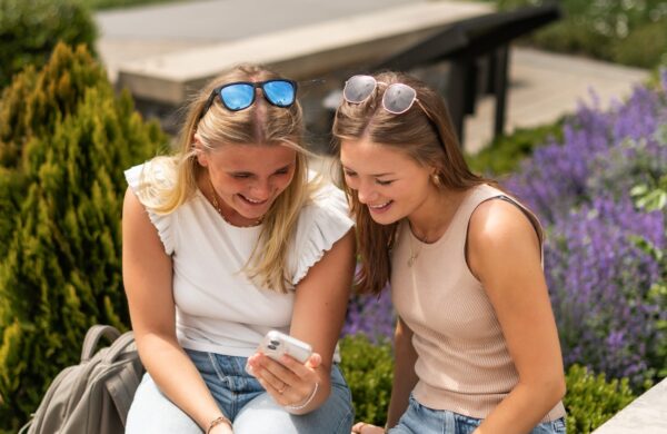 Two girl friends playing on a phone outside