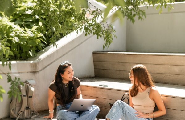 Two girl friends studying outdoors on benches outside the student union