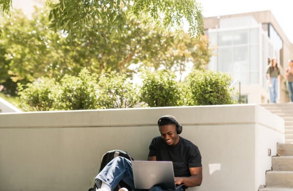 Young man studying on his laptop on an outdoor bench