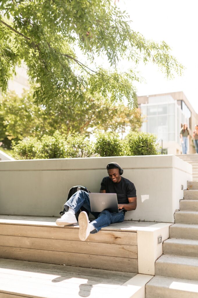 Young man studying on his laptop on an outdoor bench